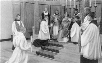De wijdingen: 9. Diakonaat (Ritus der diaken-wijding). De bisschop onderricht den wijdeling over zijne verplichtingen als diaken: nr. 1 het bedienen van Christus <Lichaam en Bloed>; het dopen en prediken; Foto Foto