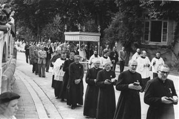 De sacramentsprocessie tijdens een KAB bedevaart naar Lourdes. Voor het baldakijn loopt pater Fidentius (met baard); Foto Foto
