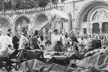 De ziekenzegen tijdens een KAB bedevaart naar Lourdes. Pater Fidentius houdt een slip van de kazuifel vast; Foto Foto