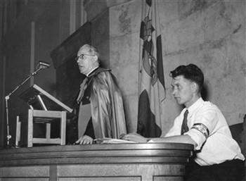 Kardinaal Alfrink spreekt terwijl KAJ voorzitter Van Bakel naast hem zit; Foto Foto