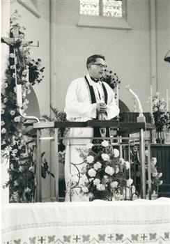 Op de dag van de viering van het 40-jarig priesterfeest van pastoor Van Welie spreekt aalmoezenier van Duinhoven van het bedrijfsapostolaat Tilburg in de kerk. Bijschrift: "Van Duinhoven aan het woord: "Van Severeind....... tot Muggenhol" "; Foto Foto