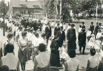 Mis ter gelegenheid van de viering van het 40-jarig priesterfeest van pastoor van Welie. De pastoor verlaat de kerk en keert terug naar de pastorie. Bijschrift: "Een stralend kerkgazon... eens een ruwe wildernis!"; Foto Foto