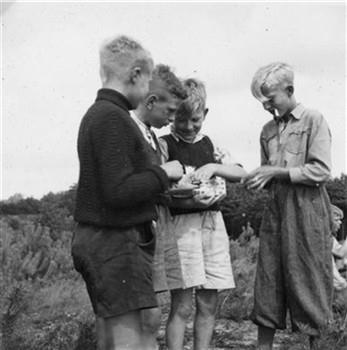 Een jongen met een sigaret in zijn mond bekijkt een voorraad snoep op een kamp van de Katholieke Jeugdbeweging; Foto Foto