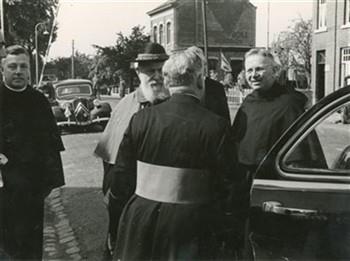 Kardinaal Tisserant brengt een bezoek aan het Apostolaat der Hereniging in Nederland. De kardinaal (met hoed) wordt hier ontvangen aan de Belgisch-Nederlandse grens. De pater rechts is de assumptionist Frans Wijnhoven. De foto's 6a1455, 6a1456, 6a1457 en 6a1458 hebben allemaal betrekking op het bezoek van de kardinaal aan Nederland; Foto Foto