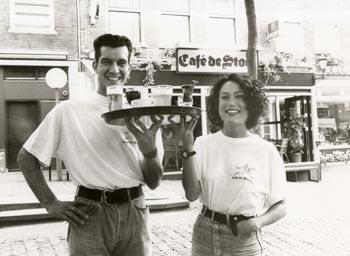 Twee medewerkers met een dienblad met glazen. Met op de achtergrond 'café de Stoof'; Foto Foto