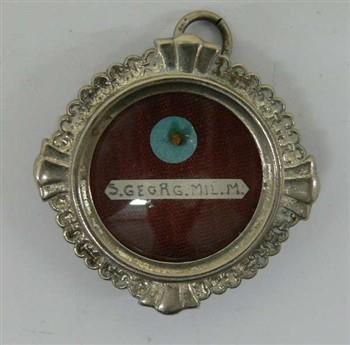 Ronde reliekhouder houdende een relikwie van de H. Joris, met tekst: 'S. Georg. mil. m.'
Binnenkant met tekst: '1h32 1953' en met waszegel houdende een wapenschild; Reliekhouder Reliekhouder