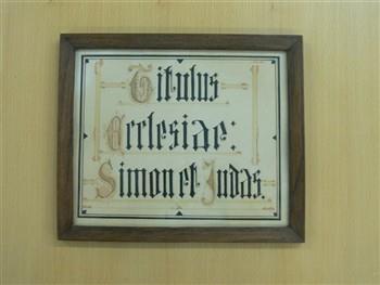 Wandbord met tekst: 'Titulus Ecclesiae Simon et Judas'.
Sticker op achterkant met tekst: 'Patronen van de kerk in Ootmarsum de H.H. Simon en Judas, Apostelen'; Wandbord Wandbord