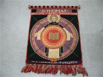 Wandtapijt houdende een afbeelding van de H. Thomas, met tekst: 'St Thomas dioc ver van RK Byzondere (sic) Onderwijzers afd. Den Haag en omstreken'. Met franjes. Aan houten roller; Wandkleed Wandkleed