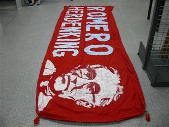 Spandoek van textiel houdende een afbeelding van aartsbisschop Romero, met tekst: 'Romero Herdenking'; Spandoek Spandoek