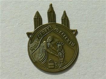 Pelgrimsinsigne met voorzijde tekst 'Amersfoort MCCCCXIV' en achterzijde 'Omroeppastoraat 't Zand 33'. En Pelgrimsinsigne met tekst voorzijde 'Amersfoort MCCCCXIV'. Met beschrijving; Pelgrimsinsigne Pelgrimsinsigne