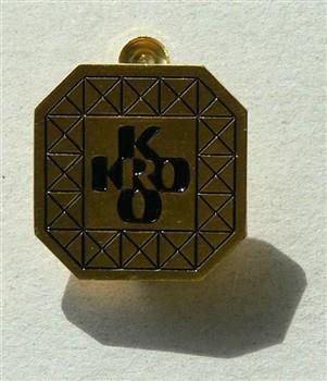 Twee buttons achthoekig met tekst 'KRO'. Eén button is koperkleurig met zwarte opschrift en de andere button heeft een witte achtergrond met blauwe opschrift; Button Button