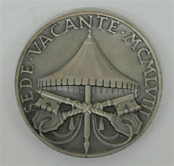 Penning houdende een afbeelding het wapen van een kardinaal, met tekst: 'Benedictus card. Aloisii Masella S.R..E. Camerarius'.
Keerzijde houdende een afbeelding van de pauselijke baldakijn en de sleutels van Petrus, met tekst: 'Sede Vacante MXMLVIII'; Penning Penning